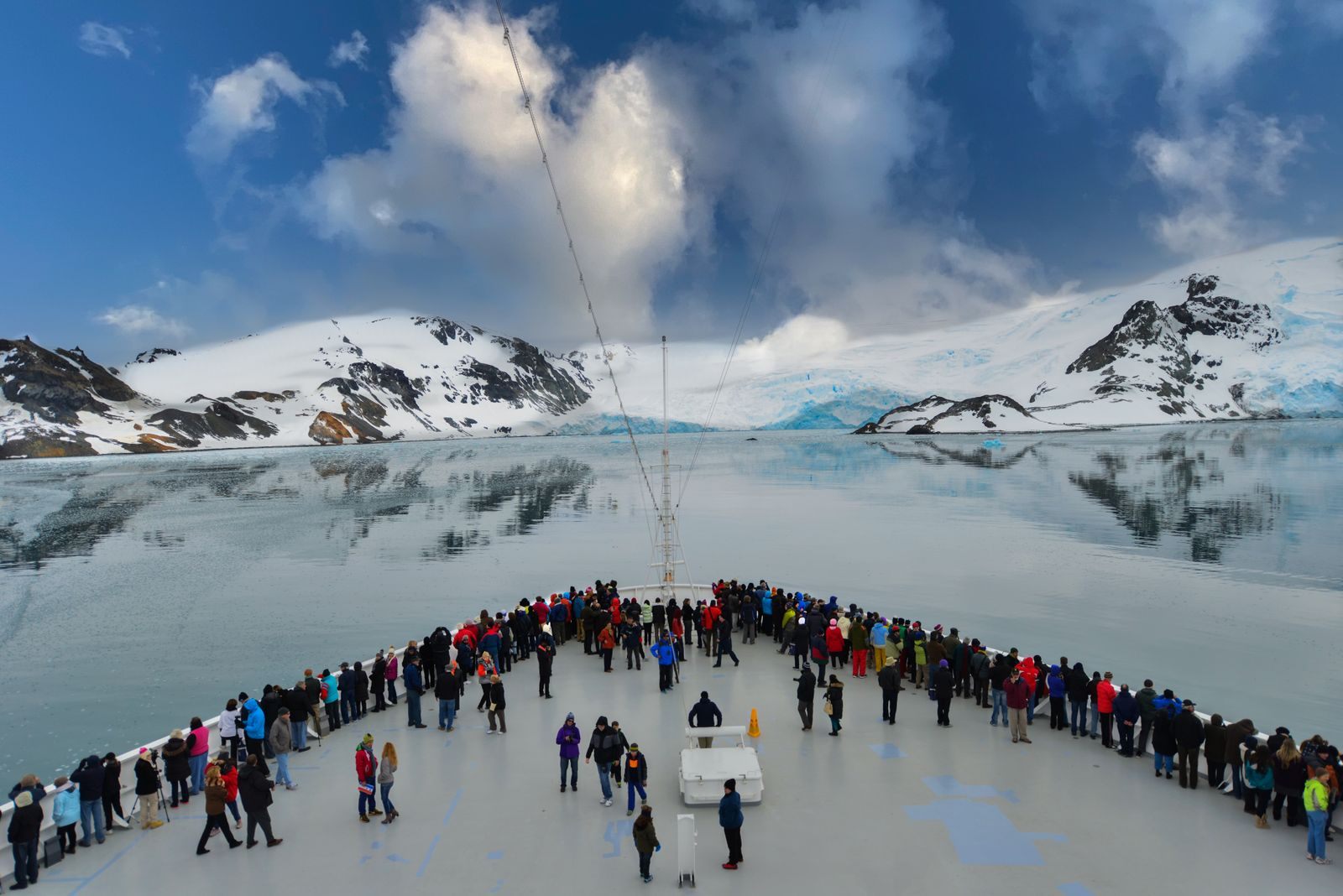Passengers on the bow of an expedition ship among snowy mountains, one of many types of cruises